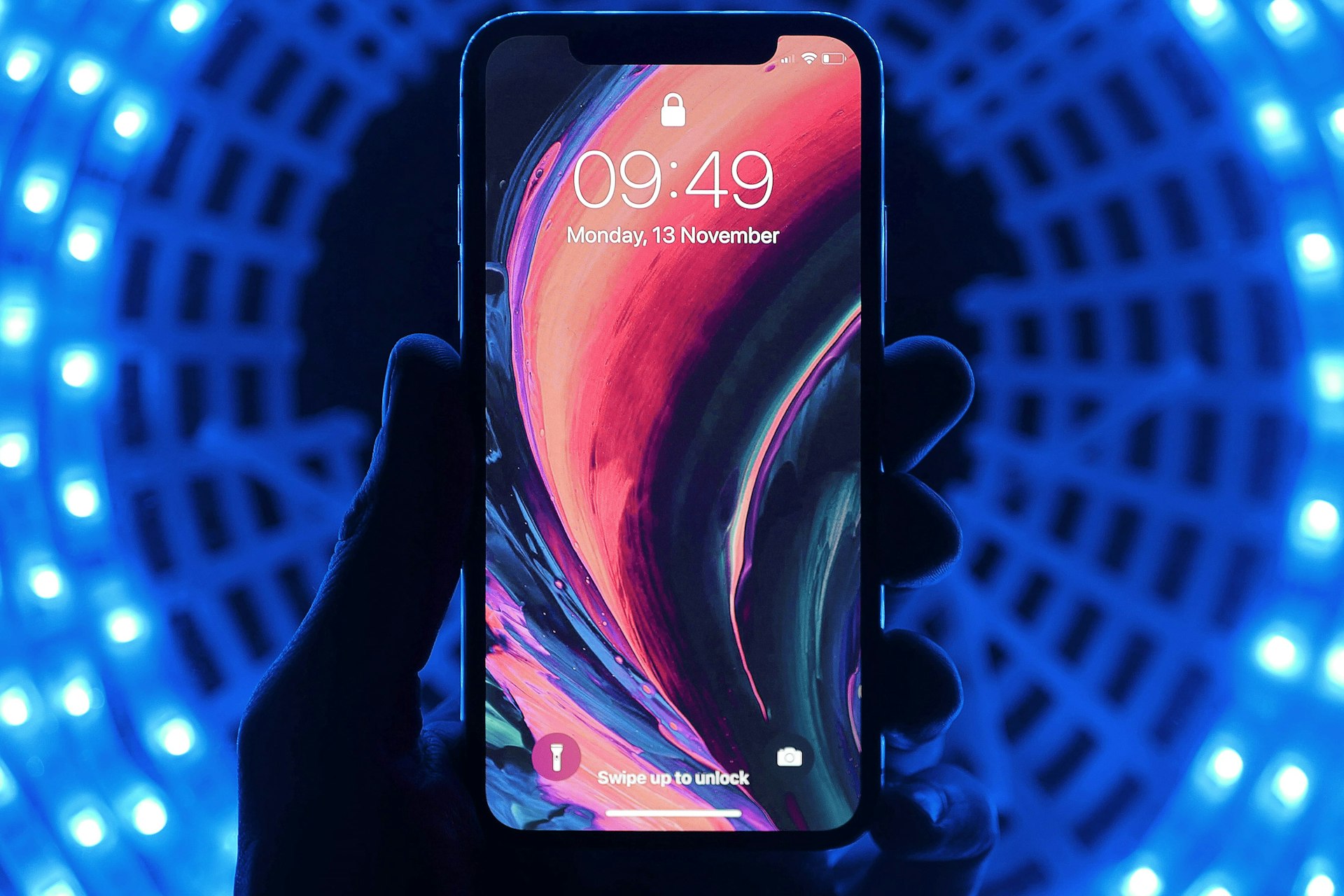 Hand hält iPhone mit Sperrbildschirm vor blauen LED-Lichtern