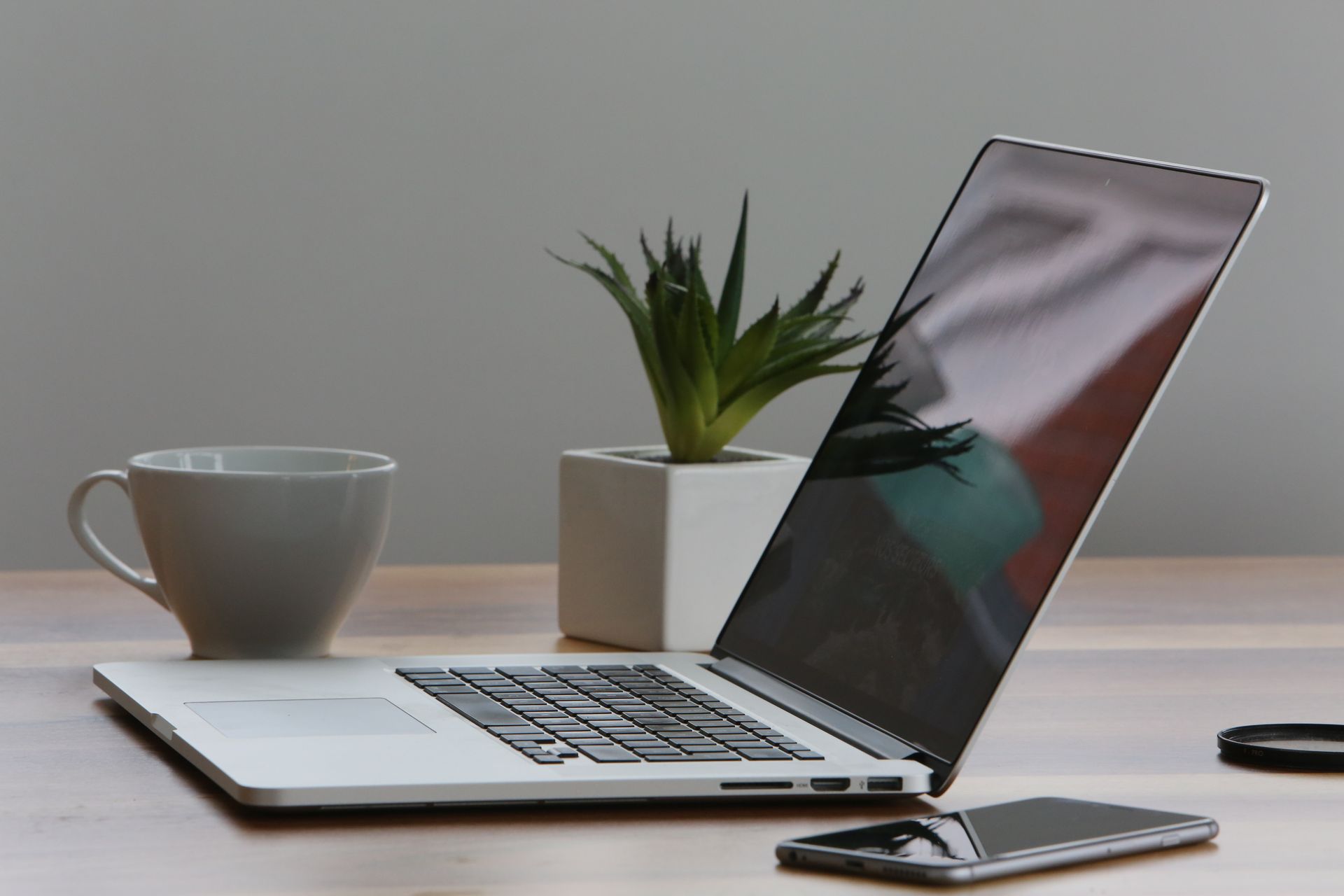 Silbernes MacBook Pro auf Holzschreibtisch mit Kaffeetasse
