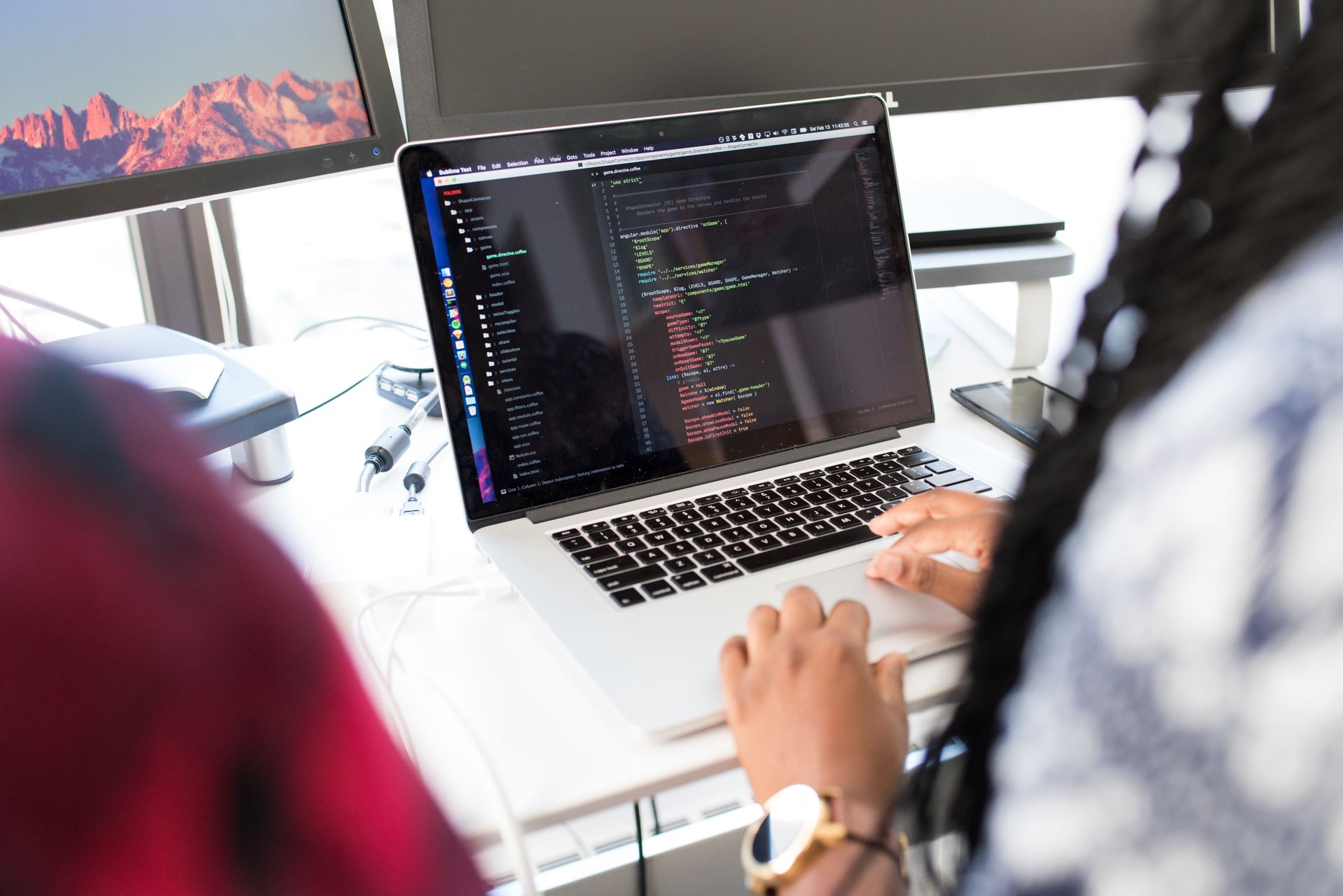 MacBook Pro mit geöffnetem Code-Editor und angeschlossenen Kabeln