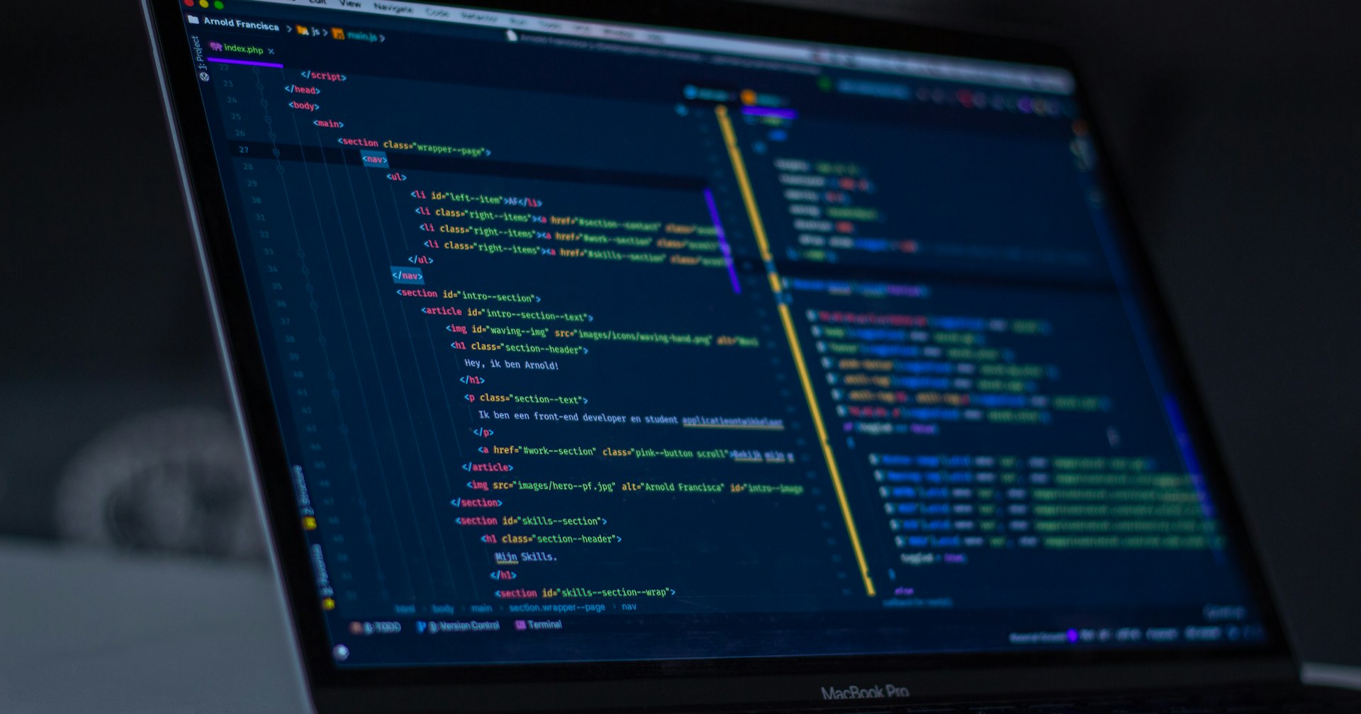 MacBook Pro screen showing a dark VS Code window with HTML and PHP
