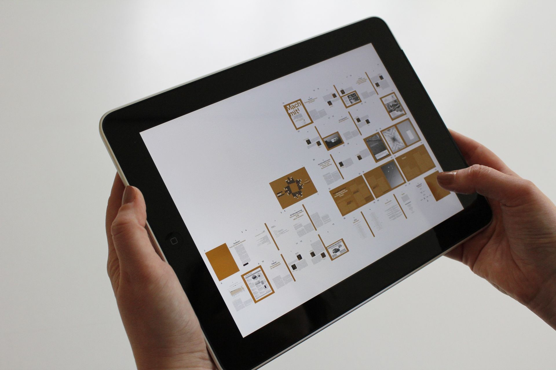 Mains tenant un iPad noir affichant une grille de diapositives