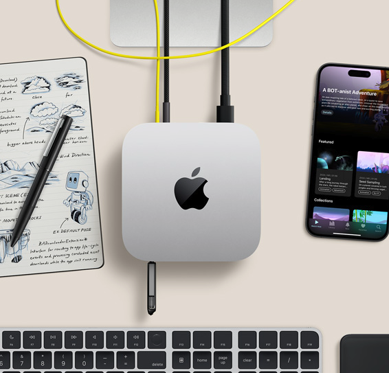 Top-down view of a silver Mac mini developer desk with iPhone, handwritten design notebook, and Magic Keyboard