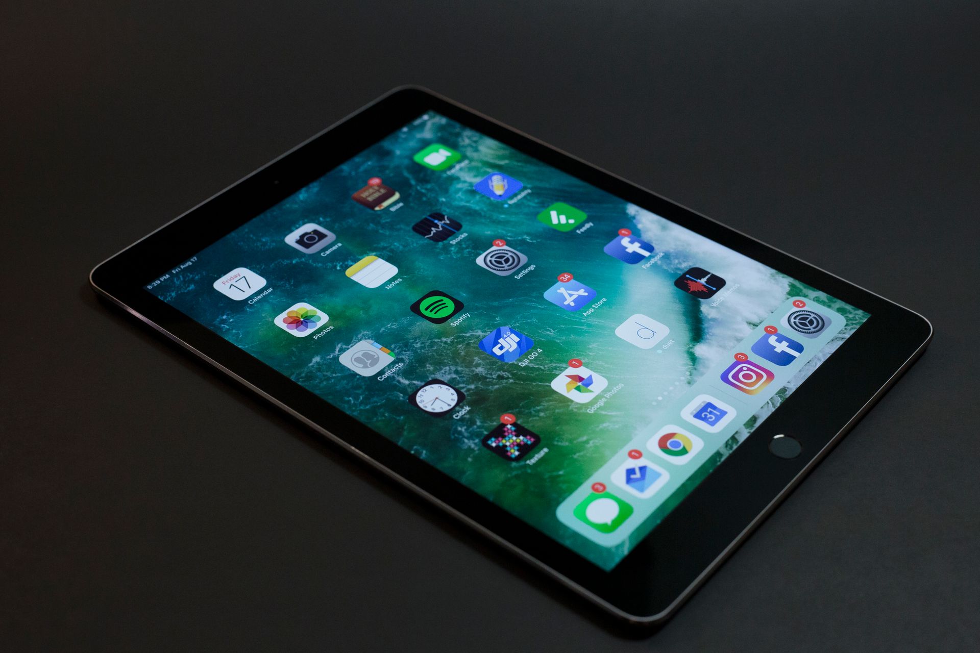 iPad на тёмной поверхности с сеткой приложений iOS